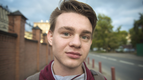 młody mężczyzna na tle zabudowa 