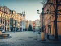 Świdnica. Ulica z kolorowymi kamienicami, świąteczna choinka, ludzie spacerujący, jasne niebo.