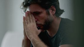 Smutny mężczyzna chowa twarz w dłoniach