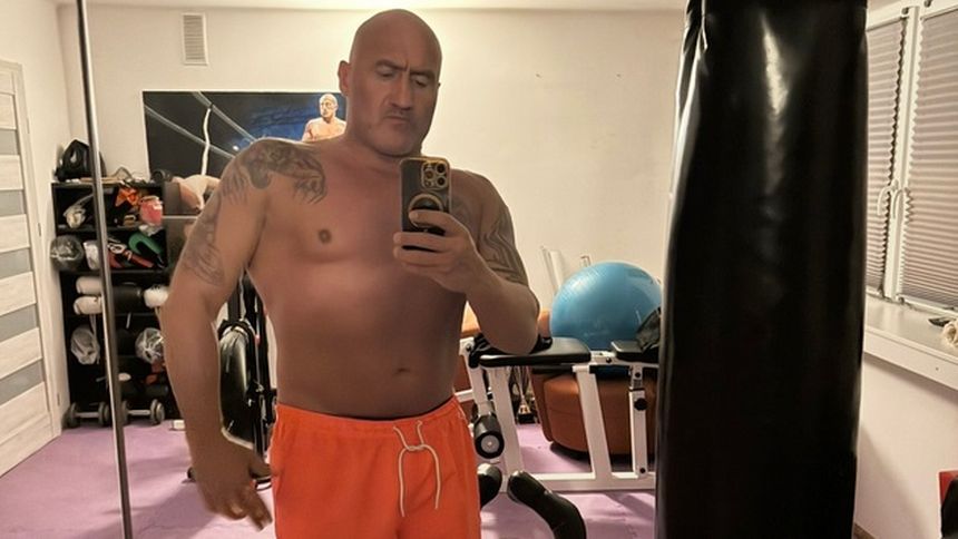 Marcin Najman w pomarańczowych szortach, robiący selfie w siłowni.