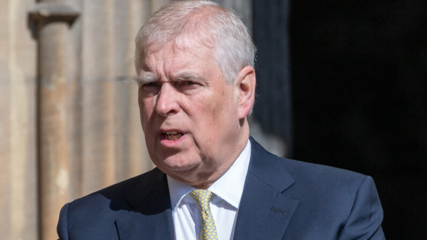 Książę Andrzej w garniturze, mówi, z tłem w postaci historycznego budynku.