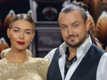 Sandra Kubicka i Aleksander Baron w eleganckich strojach na tle jasnej dekoracji.