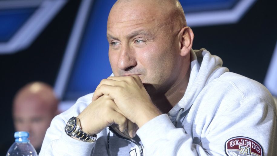 Marcin Najman z zamyśloną miną. W tle kontury innych osób.