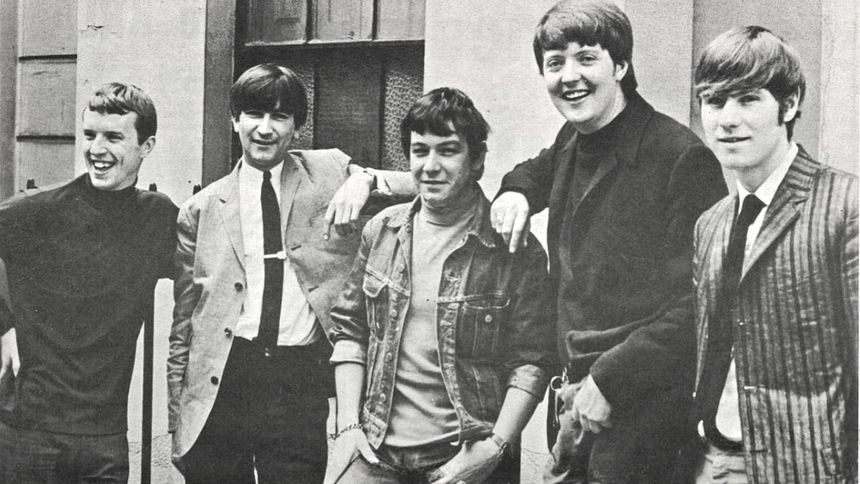 Na zdjęciu pięciu mężczyzn stojących obok siebie, uśmiechających się. Czarno-białe, retro.