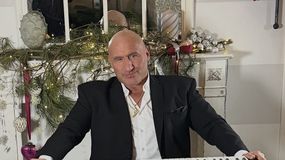 Marcin Najman w garniturze gra na keyboardzie, w tle świąteczne dekoracje.