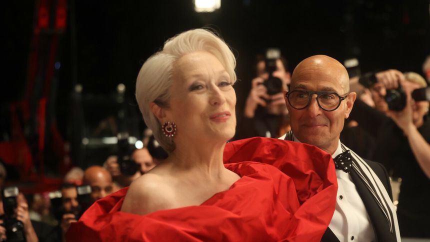 Na zdjęciu widoczna Meryl Streep w czerwonej sukience i mężczyzna w czarnym garniturze z brylantu.