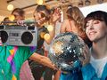 Grupa ludzi tańcząca, w tle dyskotekowa kula i boombox, radosna atmosfera na imprezie.