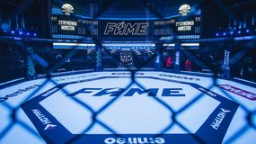 Widok na ring MMA z logiem FAME, otoczony siatką; w tle ekrany i oświetlenie.