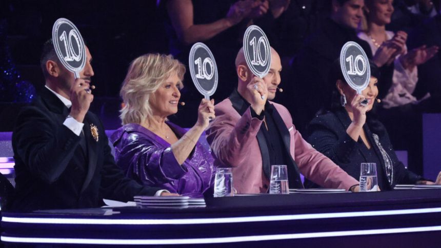 Czterech sędziów trzymających tabliczki z oceną 10 podczas programu telewizyjnego.