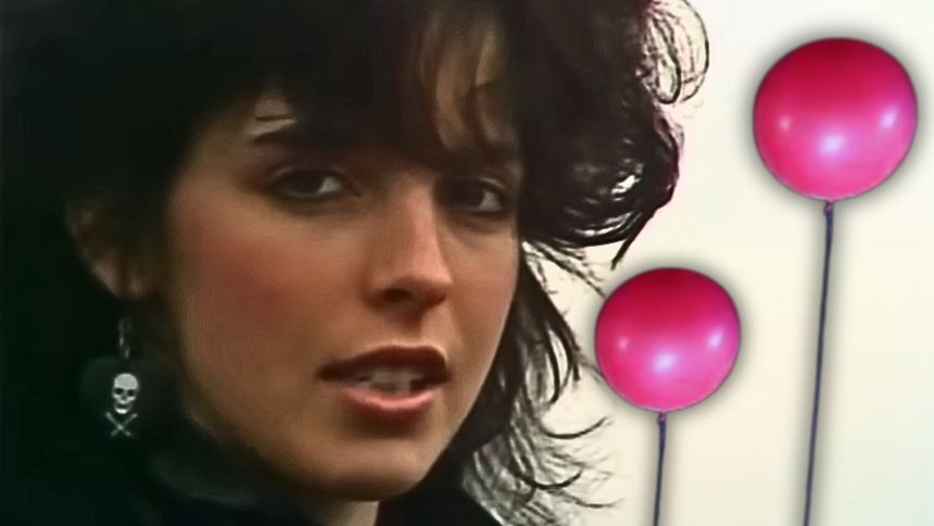 Kobieta patrząca w kamerę, a obok dwa balony