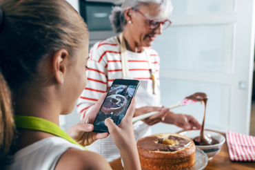 Babcia robi ciasto, wnuczka zdjęcie smartphonem
