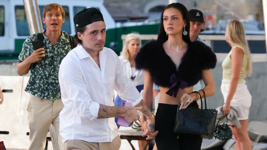 Na zdjęciu widać Brooklyna Beckhama i Nicolę Peltz, otoczonych osobami w luźnych ubraniach.