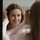 Uśmiechnięta kobieta przegląda się w lustrze