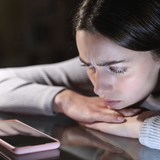 Młoda kobieta patrzy na telefon i czeka na wiadomość