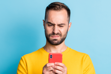 Mężczyzna patrzy w telefon z niezadowoloną miną