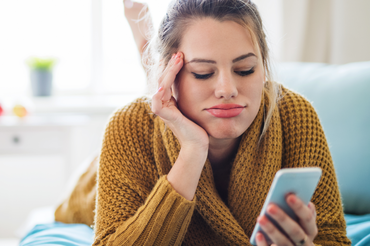 Dziewczyna patrzy w telefon z niezadowoloną mina