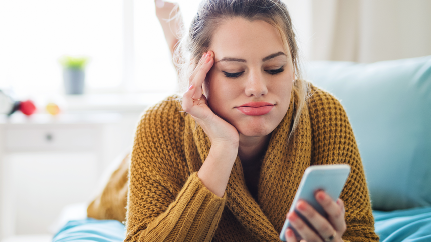 Dziewczyna patrzy w telefon z niezadowoloną mina