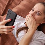 Zszokowana kobieta korzysta z telefonu - materiał poglądowy