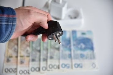 Wtyczka na tle pieniędzy - materiał poglądowy
