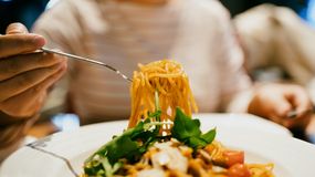 Na talerzu makaron spaghetti z ziołami. Ktoś z widelcem nabiera porcję.