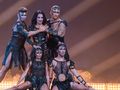 Grupa tancerzy w kostiumach, prezentujących dynamiczną choreografię na scenie.