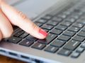 Kobieca reka naciska klawisz Enter na klawiaturze laptopa