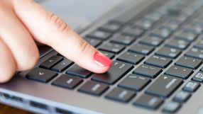Kobieca reka naciska klawisz Enter na klawiaturze laptopa