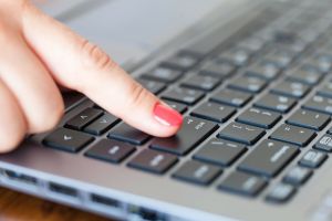 Kobieca reka naciska klawisz Enter na klawiaturze laptopa