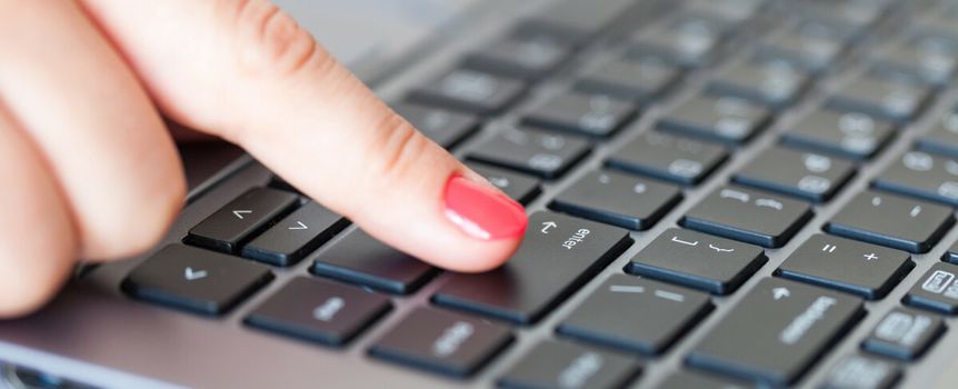 Kobieca reka naciska klawisz Enter na klawiaturze laptopa