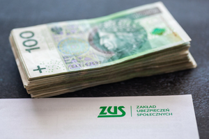 Napis i logo ZUSu z pieniadzmi w tle
