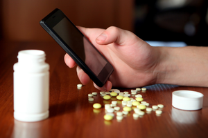 mężczyzna korzysta z telefonu, na stole znajdują się tabletki