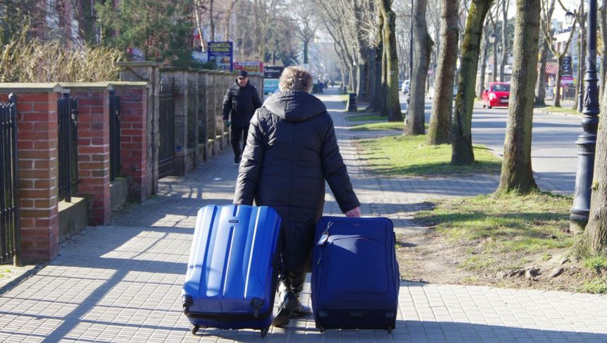 seniorka prowadzi walizki