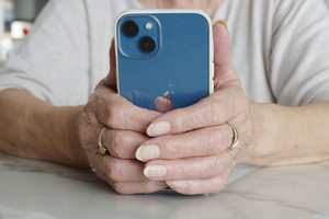 starsza kobieta trzyma telefon w dłoni 
