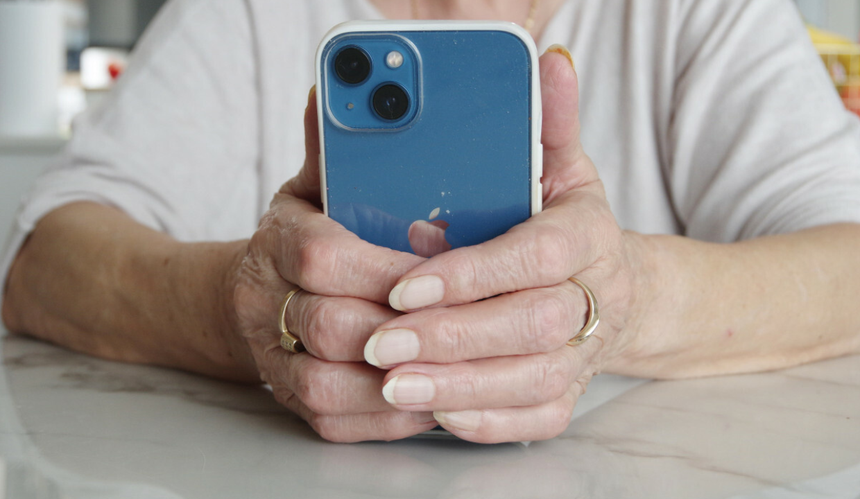 starsza kobieta trzyma telefon w dłoni 