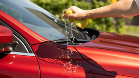 mężczyzna myje czerwony samochód