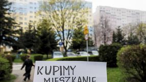 kartka z napisem "kupimy mieszkanie" na tle bloku mieszkalnego