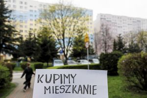 kartka z napisem "kupimy mieszkanie" na tle bloku mieszkalnego