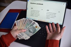 pieniądze w ręku przed ekranem komputera