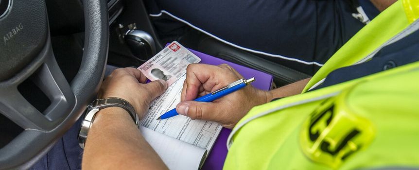 Policja wypisuje mandat kierowcy 
