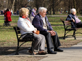 Seniorzy siedzą na ławkach 