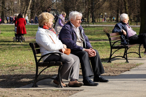 Seniorzy siedzą na ławkach 