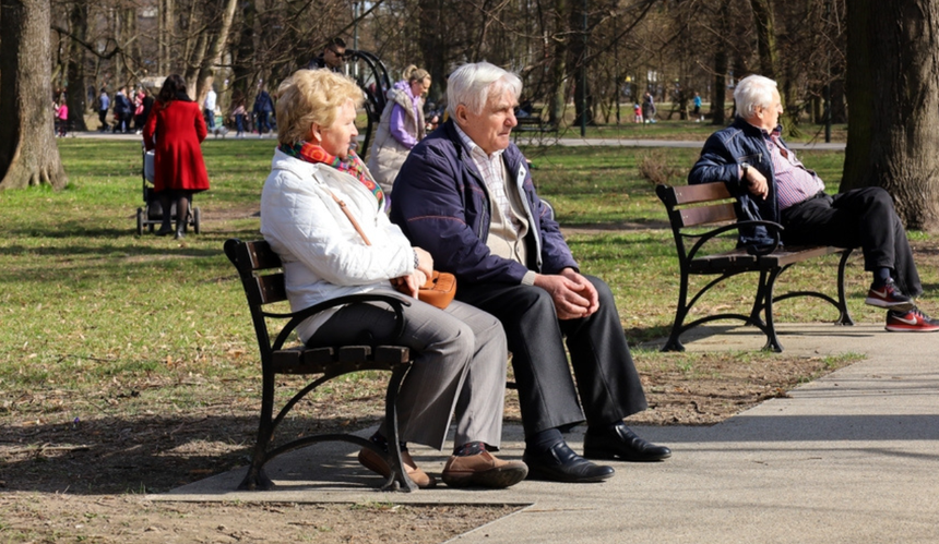 Seniorzy siedzą na ławkach 