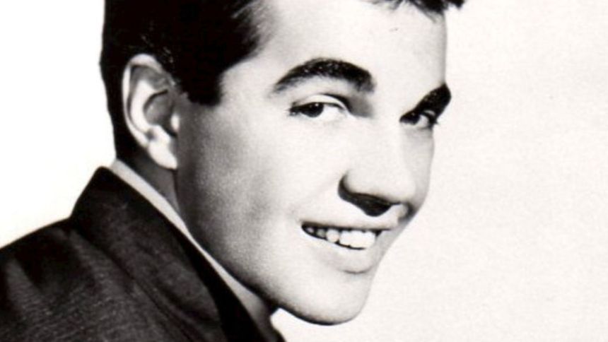 Zdjęcie czarno-białe mężczyzny uśmiechającego się w eleganckim ubraniu. 