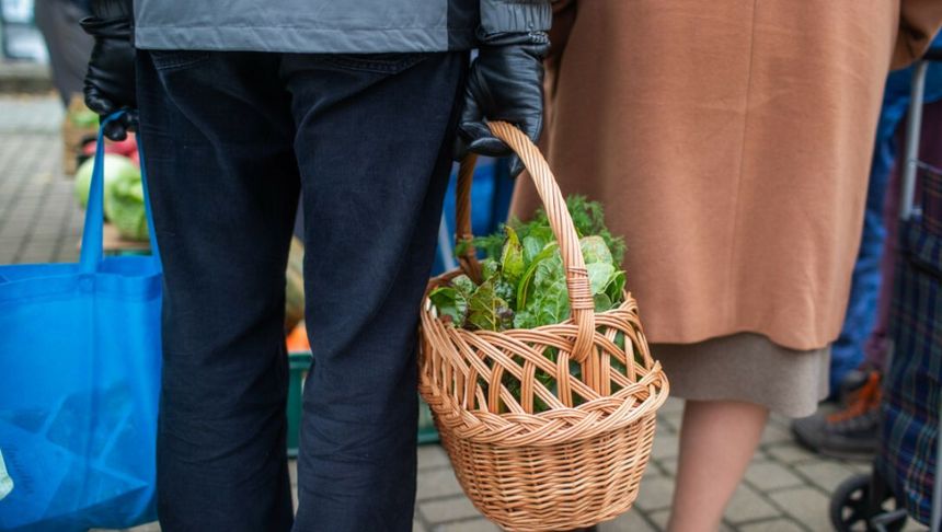 Para seinorów na zakupach na targu z koszykiem warzyw
