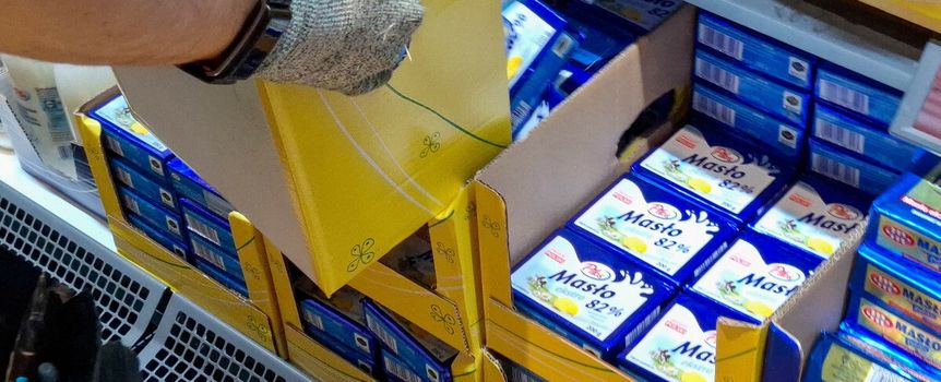 pracownik wykładający masło na półkę