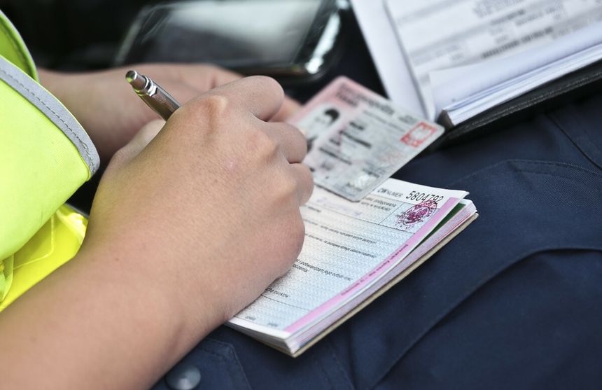 Policjant wypisuje mandat dla kierowcy
