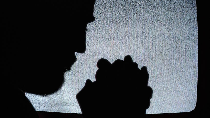 Zarys modlącego się człowieka i telewizor