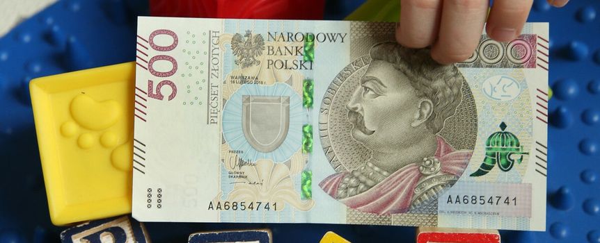 500 zł w rękach dziecka i napis "plus" z klocków