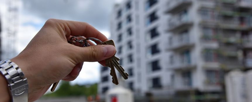 klucze trzymane przed blokiem mieszkalnym