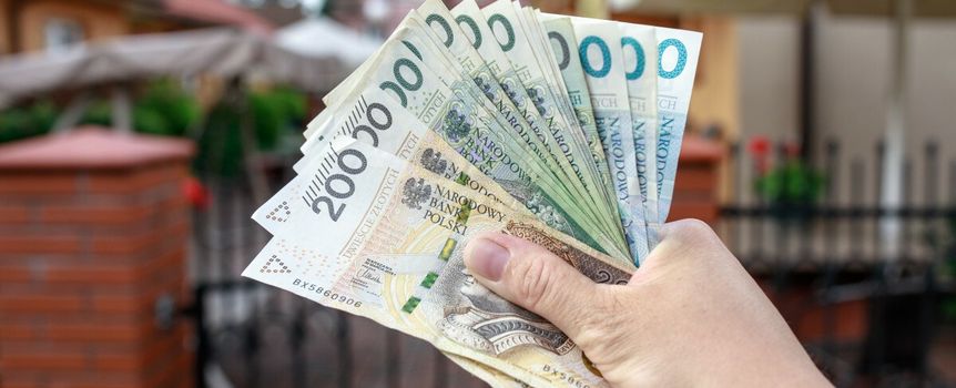 pieniądze w ręku na tle domu jednorodzinnego